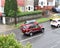 Traffic and parked cars at British brick houses on a rainy day.