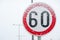 Traffic road speed limit 60 sign on the street covered with snow in danger slippery winter season close up