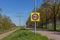 Traffic sign: maximum speed 80 between a rural road and a bicycle lane, trees, huge high voltage towers