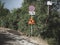 Traffic signs on the side of an uninterrupted road with trees along it