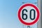 Traffic speed limit sign for restriction on 60 kilometers or miles per hour with blue sky background