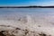 Traffic tire tracks and cracks on frozen lake surface with beautiful blue sky and lakeshore line