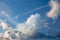 Trail from an airplane in the blue sky with relief clouds