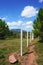 Trail along a fence through a forest clearing with mountains ahead and blue sky overhead in rural Laos