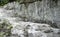 A trail in a chalk mountain with rocky ground and sheer rocky chalk stone walls.