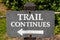 Trail Continues Sign With White Left Arrow on a Post