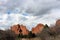 A trail leading to towering sandstone rock formations rising above pine trees and backed by cumulus clouds in Colorado Springs