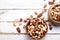 Trail mix with different kinds of nuts in brown wood bowl on scratched white wooden table background, soft daylight. Copy space.