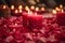 A trail of red rose petals leading to a group of lit candles. The candles are set against a dim, soft-focus background, creating a