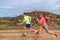 Trail run race ultra runners athletes couple running in rock path in nature landscape. Ultra runner people competing on