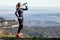 Trail runner drinking water while looking landscape from mountain peak