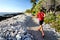 Trail runner jogging on running path at beach in white coral rocks at hawaii travel destination. Male athlete from