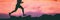 Trail runner legs of man athlete running on rocks in sky pink clouds background. Panoramic banner silhouette of run