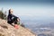 Trail runner sitting and taking a break while looking landscape from mountain peak