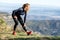 Trail runner stretching while looking landscape from mountain peak