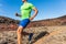 Trail runner ultra running man athlete on desert path in dry heat landscape. Male sports person training outdoors. Closeup of body