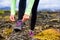 Trail runner woman getting ready to run on rocky mountain mud race in autumn. Athlete tying up laces of running shoes. Closeup of
