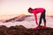 Trail runner woman tying running shoes laces getting ready to run on mountains nature in summer sunset dusk landscape. Nature