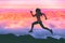 Trail running woman athlete runner exercising in mountains landscape background at sunset with pink color sky clouds