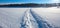 Trail from a snowmobile on a frozen and snowy river bed.