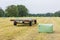 Trailer in grass field with plasticized hay bales