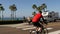 Trailer, people riding bikes, ped crossing zebra, waterfront road. Ocean beach palms, California USA