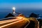 Trailing car lights lead to Cabo Ortegal lighthouse at night