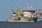 Trailing suction hopper dredger in the Weser estuary with container vessel and port facilities in the background