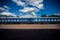 Train with blue wagons standing on platform against background of beautiful sky