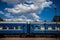 Train with blue wagons standing on platform against background of beautiful sky