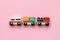 Train children toy, preschool kids game. Locomotive and carriages, wooden colorful blocks construction on pink color