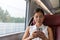 Train commute first class woman using phone texting on mobile phone app work on online wifi device. Asian businesswoman