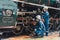 Train engineer team working service maintenance old dirty vintage classic steam engine locomotive in train repair workshop at