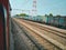 A train at halt and a gtanding on another track. A railway track lying empty and electrical transmission lines above.