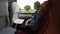 Train passenger woman on trip looking out the window green hills and trees in background -