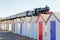 Train passing colorful beach huts in