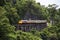 Train running on track between hellfire pass mountain and riverside Sai Yok waterfall and Khwae river bring thai people and