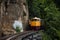 Train running on track between hellfire pass mountain and riverside Sai Yok waterfall and Khwae river bring thai people and