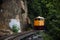 Train running on track between hellfire pass mountain and riverside Sai Yok waterfall and Khwae river bring thai people travelers