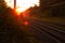 The train rushes by rail through a beautiful morning forest illuminated by the orange rising sun