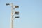 Train semaphore light with six lamps at a high gray concrete pillar against blue sky