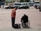 A train station employee communicates with an elderly man in a wheelchair. Assistance to