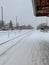 Train station platform in Chicago suburbs during snowstorm, with commuter walking along tracks