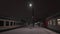 Train station at snowy night. Lonely human figure walking on platform and going into the railway wagon.