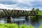A train track crossing over a New Hampshire river on bright cloudy blue day