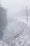 Train tracks in winter, snowing. Slope and fallen tree