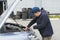 Trainee auto mechanic works in a garage, outdoors. Automobile Repair Service Concept