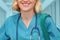 Trainee surgeon with eyeglasses in a blue uniform with books and a bag on the background of a blurred corridor of the clinic