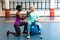 Trainer assisting disabled senior woman to exercise with dumbbell in sports center