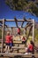 Trainer assisting girl to climb monkey bars during obstacle course training